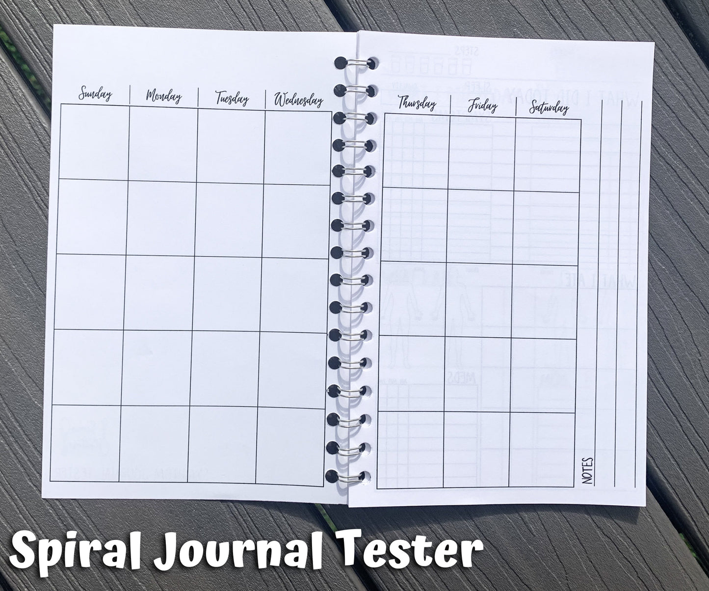 The spiral journal tester is shown open to the calendar page. There are 7 columns, 5 rows deep of squares with no dates. At the top of each column are the days of the week, but no color background. On the right page next to the box of squares you there are 3 vertical lines lining perpendicular to the way info would be written in the boxes. Notes is written on the left of the top line when facing to write.