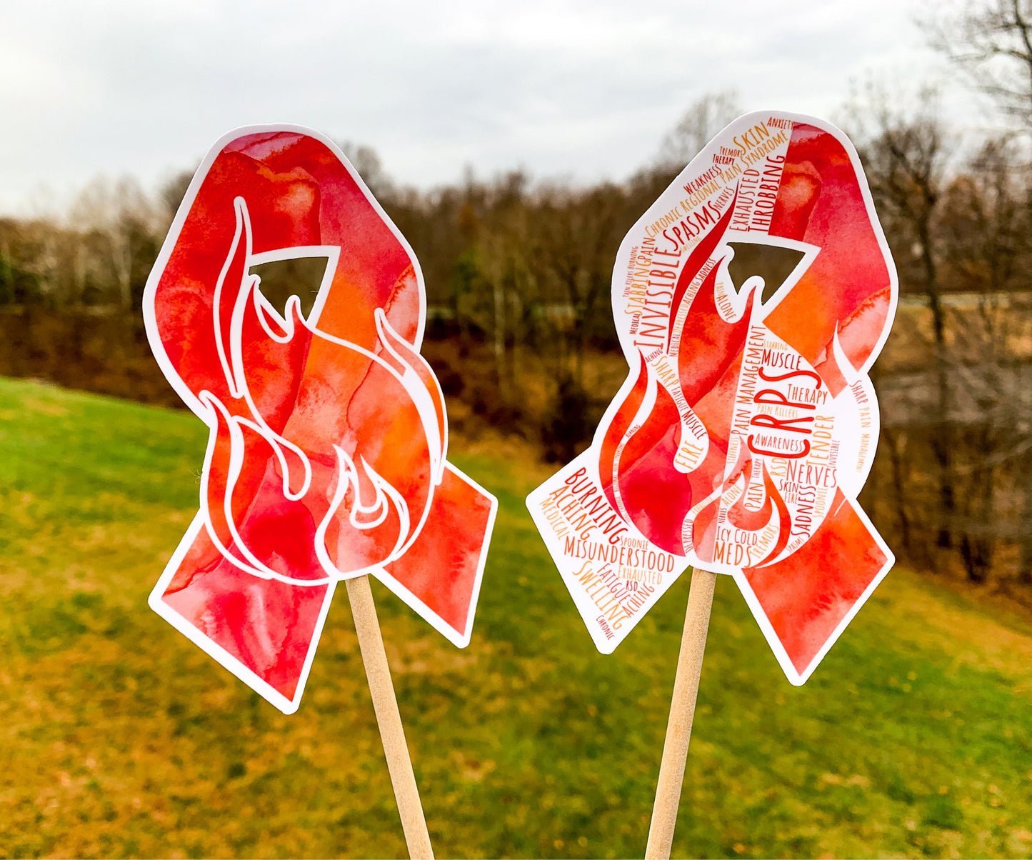 The word cloud and watercolor designs are shown on 2 sticks. Both ribbons feature an orange red awareness ribbon with fire in the center. The word cloud design on the right is split in half with a word cloud on the left half of the ribbon and heart beat and right half of the flame.