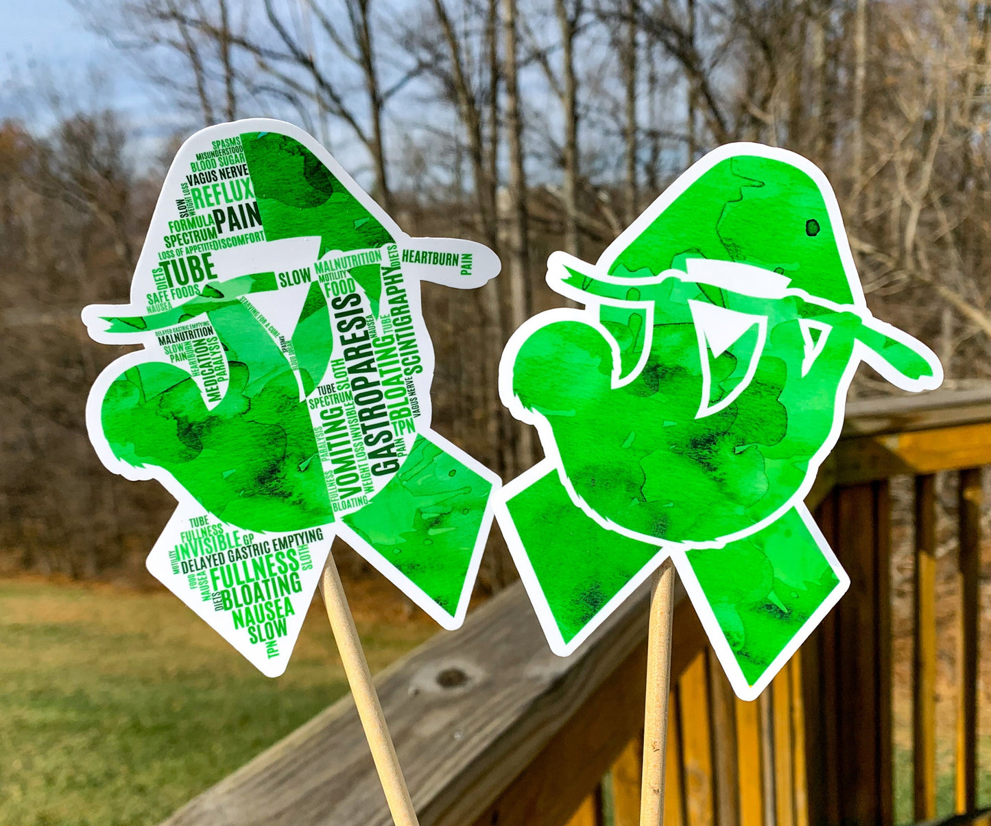 The word cloud and watercolor designs are shown on 2 sticks. Both ribbons feature a green color awareness ribbon with a hanging sloth in the center. The word cloud design on the left is split in half with a word cloud on the left half of the ribbon and right half of the sloth.