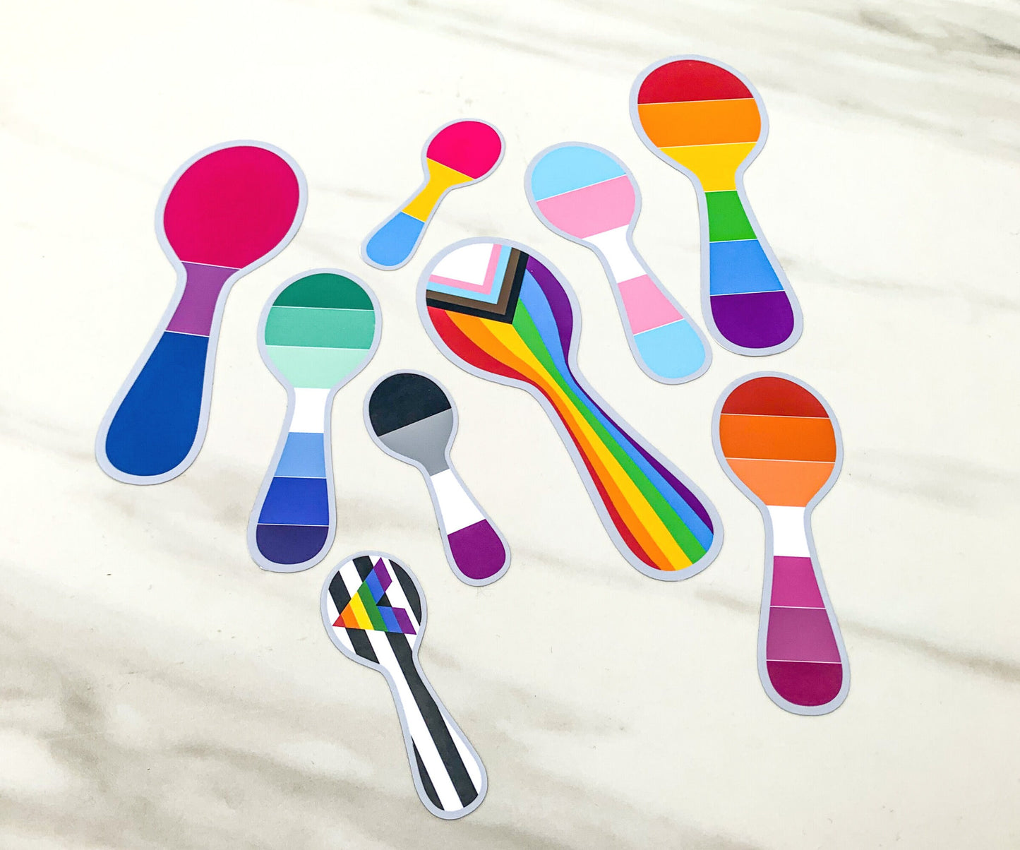 The same 9 stickers from the first photo are shown on the marble surface without the sticker paper, they have a clean grey outline.
