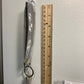 A grey keychain is shown hanging on a small command hook on the wall. A ruler is shown next to it, you can see that excluding the key ring it measures about 6 inches