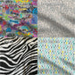 The 4 fabric options are shown in a wider view. The top left is the adaptive graffiti. You can see words like out of order, roll model with a wheelchair for the o, spork skull and cross bones that says spork off, fall risk, a sleepy panda that says there's a nap for that, and other funny cute and colorful designs on a grey brick background. The other fabrics are described in the alt text of other photos are are described by their names.