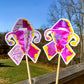 The word cloud and watercolor designs are shown on 2 sticks. Both ribbons feature a magenta/pink color and irregular yellow border on the edges. The design an awareness ribbon with a uterus in the center. The word cloud design on the left is split in half with a word cloud on the left half of the ribbon and right half of the uterus. 