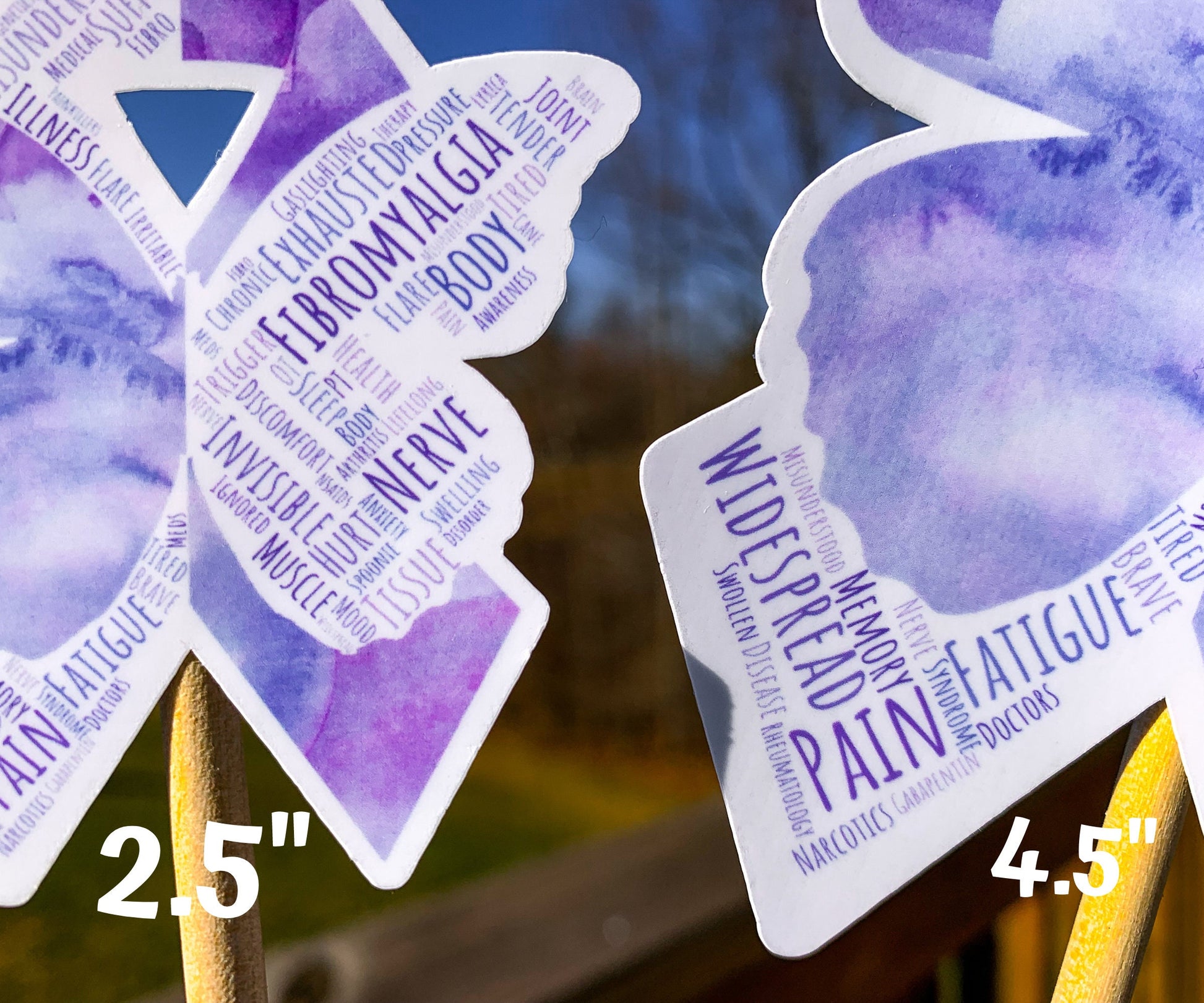 A close up of the 2.5 and 4.5 in word cloud ribbons are shown. You can see the words clearly in matching shades of purple. The words are things like Nerve, Widespread, Memory, Fatigue, Chronic, Fibromyalgia, Tissue, Spoonie, Pressure, Gaslighting, Illness, Flare, Misunderstood, Disease, and more. 