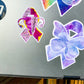  The Adenomyosis and Fibromyalgia ribbons are shown on a silver laptop. The Adenomyosis ribbon (left) is shown in size comparison to the larger Fibromyalgia (right) sticker.