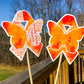The word cloud and watercolor designs are shown on 2 sticks. Both ribbons feature an orange color awareness ribbon with a butterfly in the center. The word cloud design on the left is split in half with a word cloud on the left half of the ribbon and right half of the butterfly.