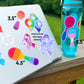 The teal waterbottle is shown next to a silver laptop with several stickers on it. The stickers have sizes labeled next to them. A 4 1/2 inch rainbow spoon and 3 1/2 inch lesbian spoon sticker are shown on the laptop and the 4 1/2 inch bisexual and 3 1/2 trans pride spoon stickers are shown on the waterbottle. The autism, adenomyosis, CRPS, POTS, and Fibromyalgia stickers can be seen on the laptop with a note that says check out our awareness stickers.