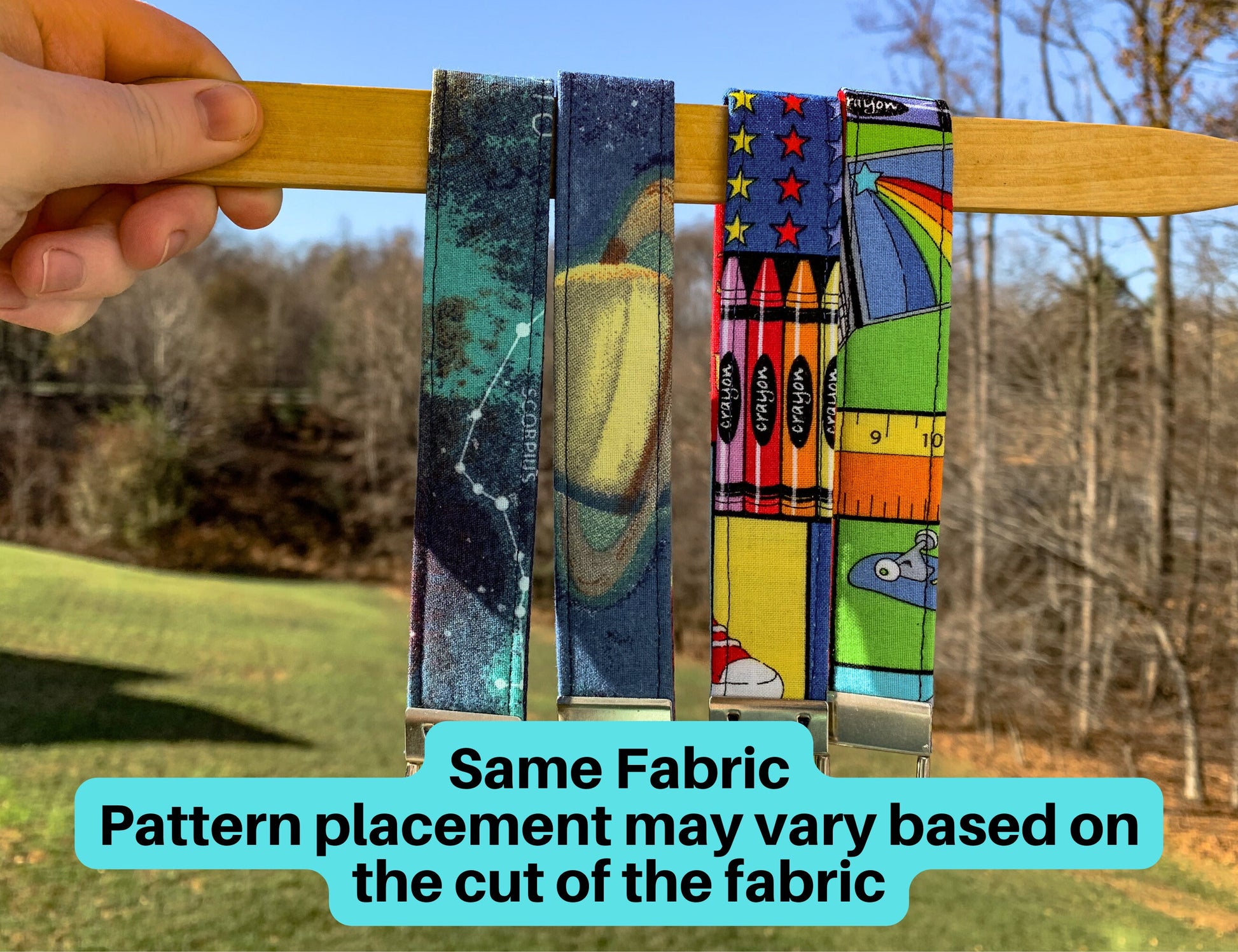Key Fobs 2 of each are shown in the fabric space blue and teacher are shown. Text says same fabric, pattern placement may vary based on the cut of fabric. On the left space wristlet you can see the constellation Scorpius an on the right one you can see the planet saturn. On the left teacher fabric you see crayons, stars, and a shoe. On the right one you can see a rainbow, ruler, and skateboard. 