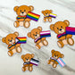 7 pride flag bears are shown on a marble surface. They each have different pride flags that match their bow ties.